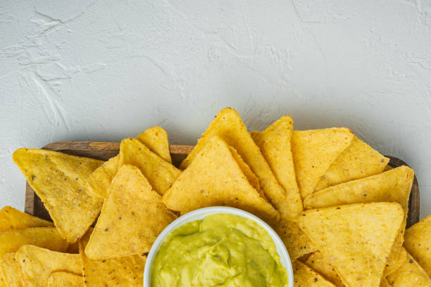 istock Mexican crispy snack, nachos chips and cheese guacamole avocado sauce, on white background, top view or flat lay with copy space for text 1294399854