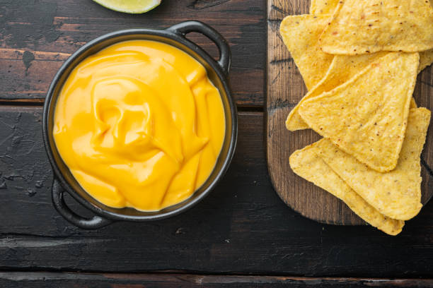 Tortilla chips with cheese dip, on old wooden table, top view or flat lay Tortilla chips with cheese dip sauce, on old wooden table, top view or flat lay cheese dip stock pictures, royalty-free photos & images