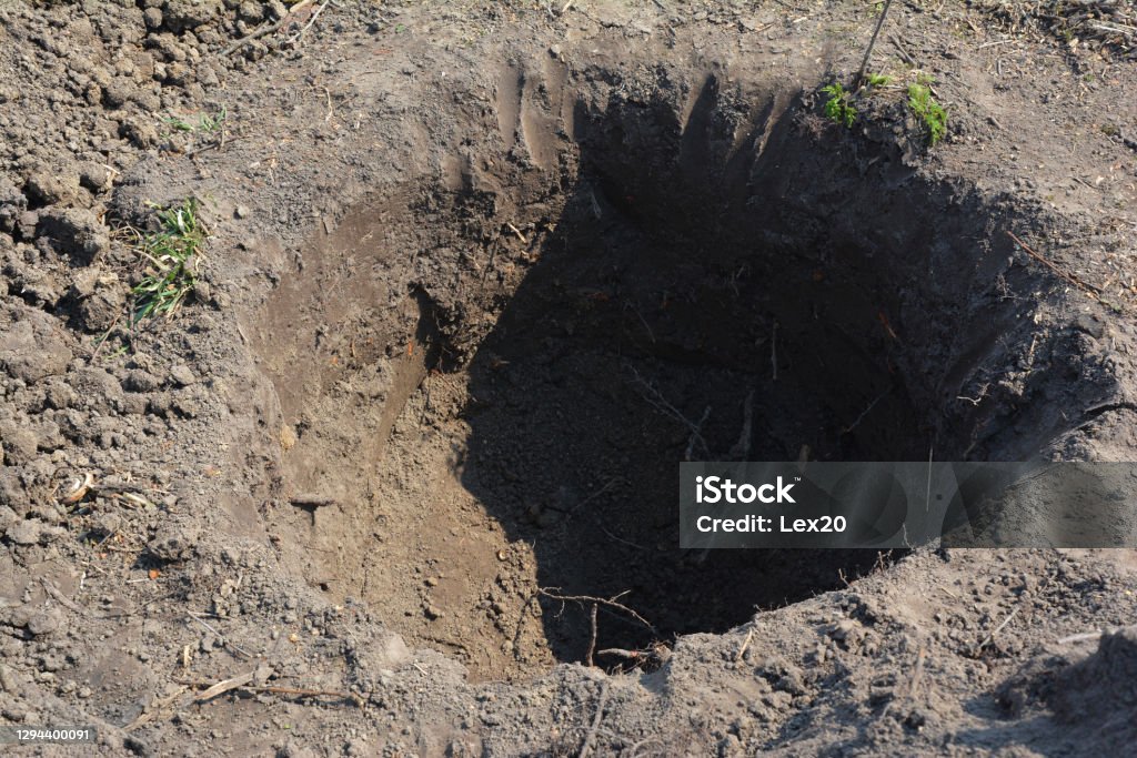 Digging a round big hole spare enough for roots to plant a tree in autumn. Hole Stock Photo