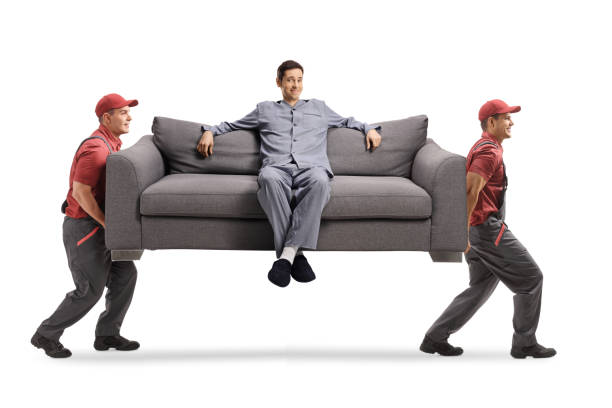 istock Movers carrying a sofa with a young man in pajamas sitting 1294400374