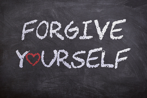 Forgive yourself phrase handwritten in white on school blackboard