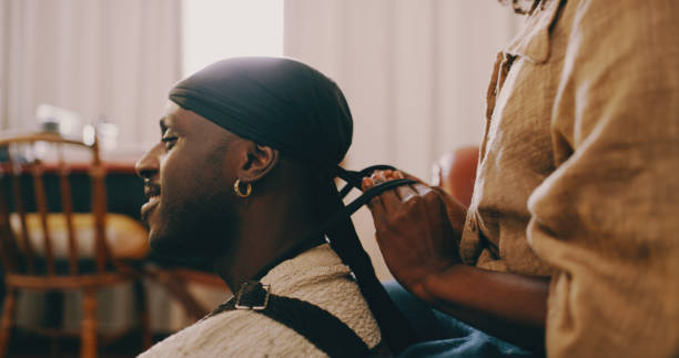 My queen keeps me looking good Shot of a young woman tying a hair wrap on her husband in the living room at home do rag stock pictures, royalty-free photos & images