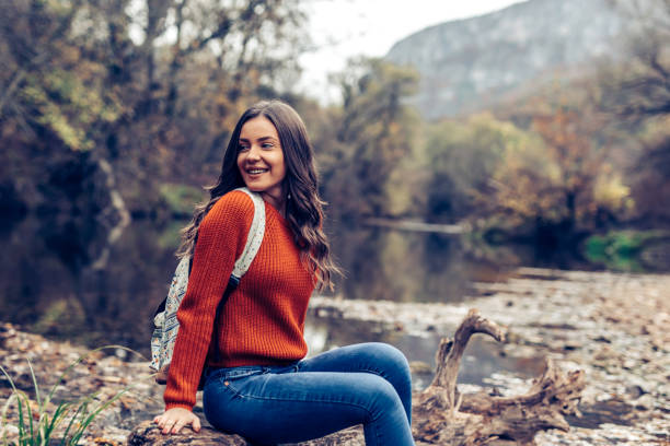 istock Young female with backpack enjoys by the river 1294402069