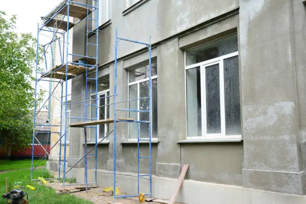 Renovating the facade of a building by applying stucco finish, plastering and finishing the exterior walls using scaffold or staging.