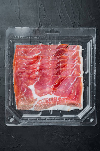 istock Slices of prosciutto, on black background, top view 1294404971