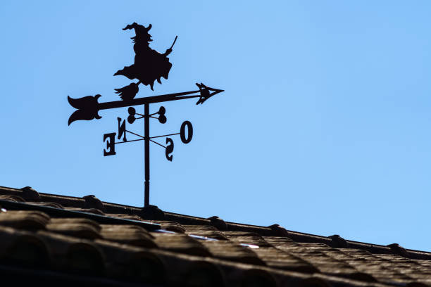 vane auf dem dach des hauses im freien mit hexe und pfeil zeigt die richtung des windes. - roof roof tile rooster weather vane stock-fotos und bilder