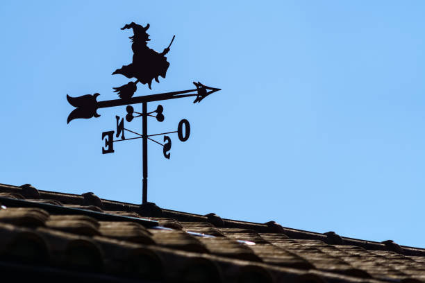vane on roof of house outdoors with witch and arrow pointing the direction of the wind. - roof roof tile rooster weather vane imagens e fotografias de stock