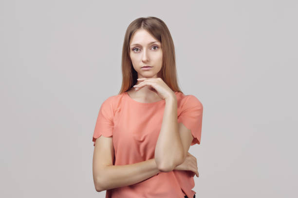istock Pensive blond girl with thoughtful expression, keeps hand on chin, plans something or makes choice 1294406358