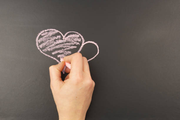 istock Hand draws a heart in chalk on a black background, with copy space. 1294406461