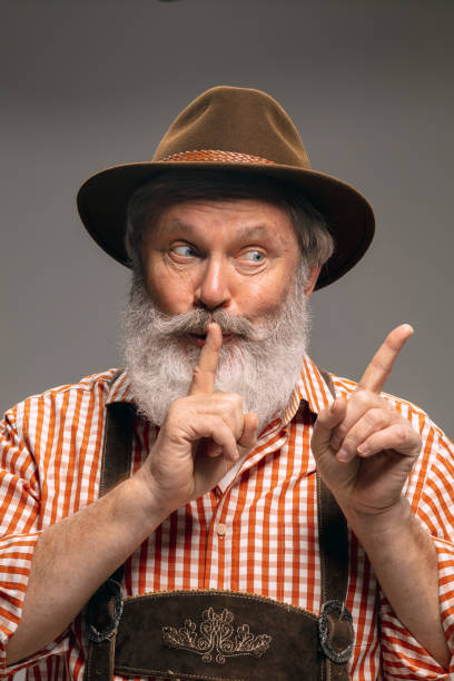 istock Happy senior man dressed in traditional Austrian or Bavarian costume gesturing isolated on grey studio background 1294407192