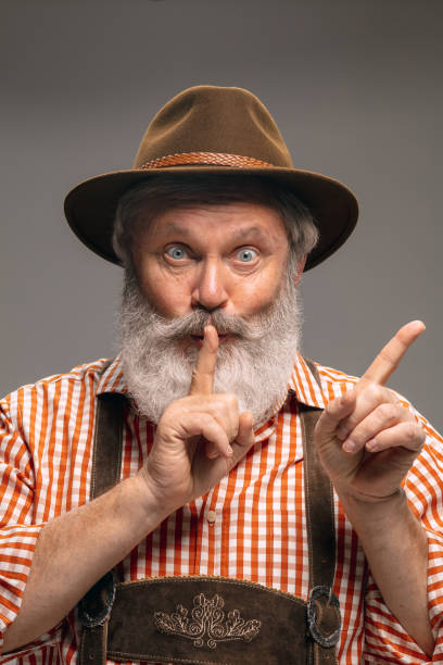 istock Happy senior man dressed in traditional Austrian or Bavarian costume gesturing isolated on grey studio background 1294407199