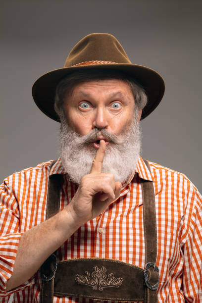 istock Happy senior man dressed in traditional Austrian or Bavarian costume gesturing isolated on grey studio background 1294407201