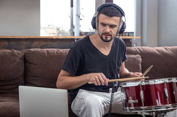 istock A young man with headphones learns to play the drum using online lessons. 1294407277