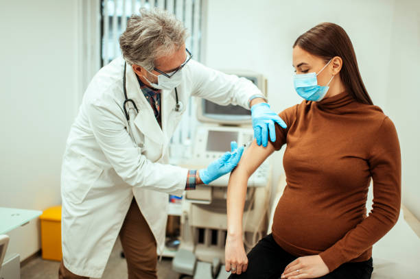 врач, дать инъекцию беременной женщине - doctors office 50s adult caucasian стоковые фото и изображения