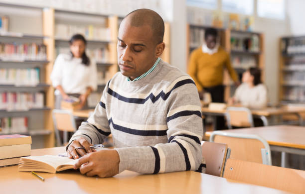 istock Focused adult latin american student studying in library 1294409953
