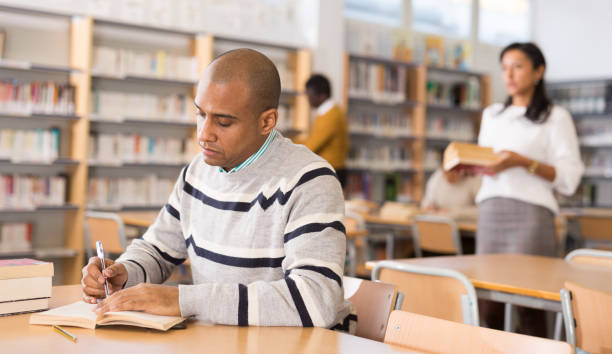 istock Young adult man studying in public library 1294409954