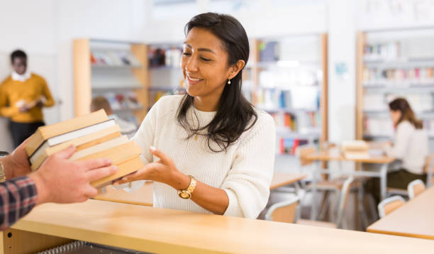 giovane donna adulta che restituisce libri in biblioteca - bibliophile foto e immagini stock