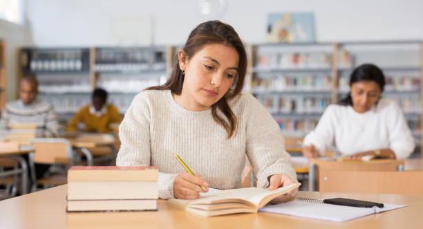 istock Young latin american woman studying in university library 1294410088