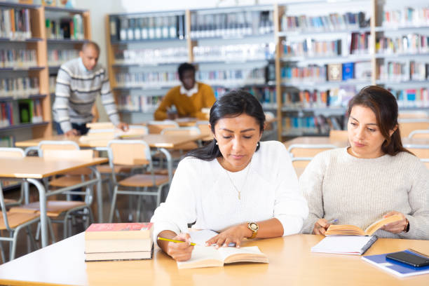 istock Two women looking for information in books in public library 1294410179