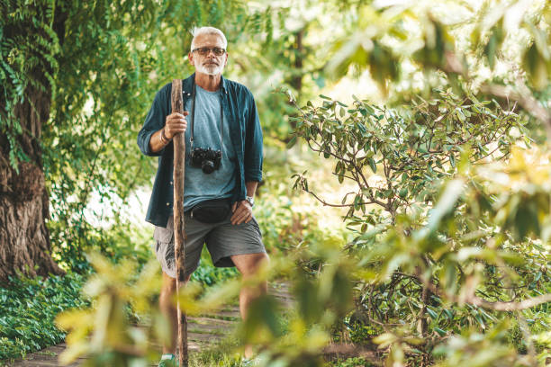 istock Retired and active, walking along the trail in the forest. Gray-haired man with a beard on vacation 1294410212
