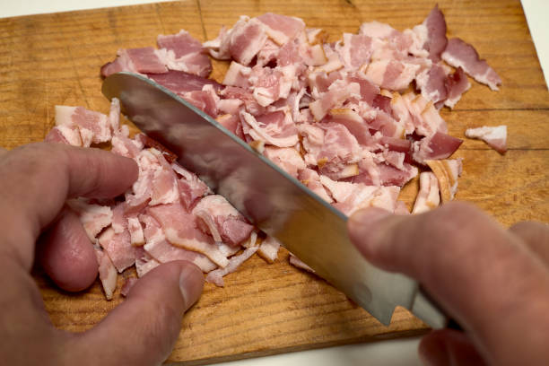 istock Man's hands cutting bacon on a wooden board 1294410420