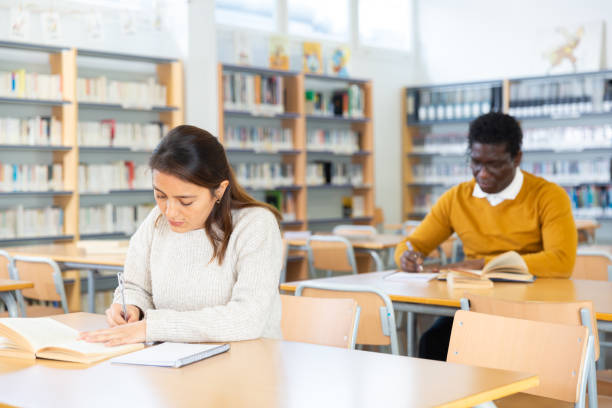 istock Young hispanic woman looking for information in books in library 1294411075