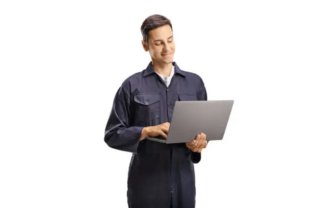 Young male worker in an overall uniform with a laptop computer isolated on white background