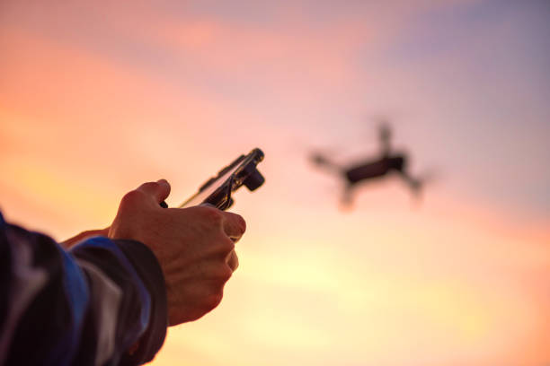 homme de plan rapproché exploitant un drone avec la télécommande dans le coucher du soleil. - drone photos et images de collection