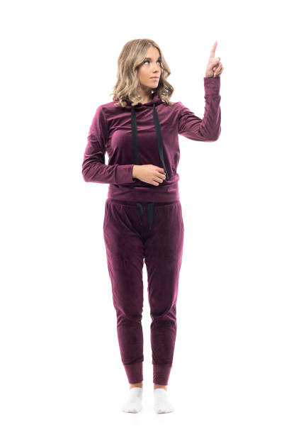 Young beautiful woman in sweatsuit home clothes looking up using touch screen with finger