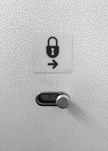 Photo of Airplane cabin lavatory lock door sign and door latch to lock and unlock.