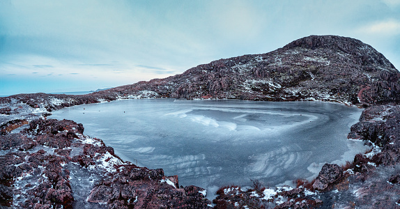 Frozen clear mountain lake, panoramic winter view. Amazing Arctic landscape with a high-altitude frozen lake. Teriberka.