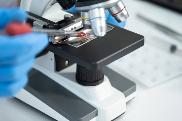 istock Young man using a microscope to see coronavirus (Covid-19) in a laboratory. He drops the dilution of blood samples in the glass. Researchers find a vaccine to prevent the virus. 1294420309