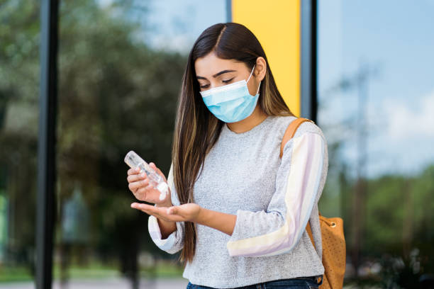 istock College student wearing face mask while applying hand sanitiser 1294421852