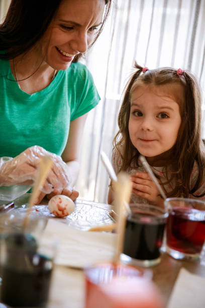 istock Little girl looking at camera while dying Easter eggs with her mother 1294421920