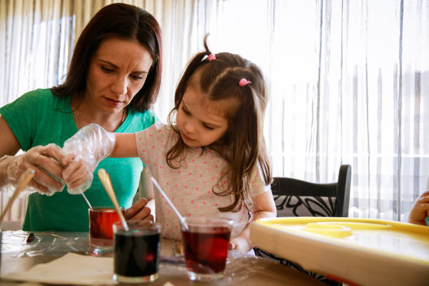 istock Little girl and her mother dying Easter eggs together 1294422037