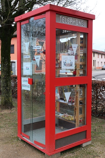 Old red telephone booth transformed into a book exchange point, town of Polliat, department of Ain, France