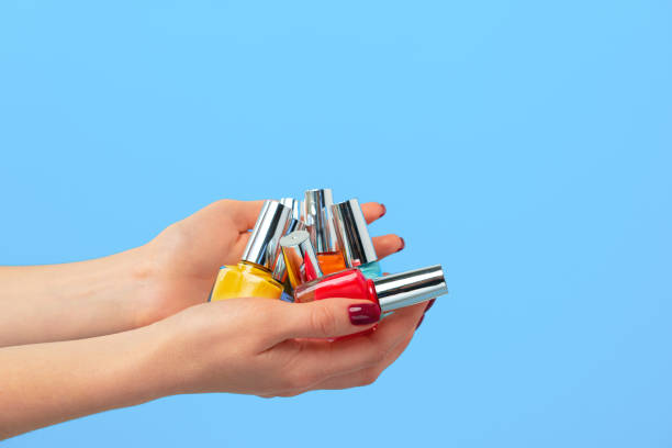istock Female hand holding nail polish against blue background 1294422719