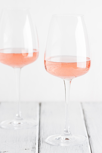 Rose wine in glasses on a white old wooden table. Selective focus. Wine tasting concept