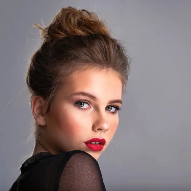 Beautiful girl with brown har. Fashion model with bright makup posing in the studio.  Attractive thin woman looking at the camera. Pretty caucasian girl with red lipstick.
