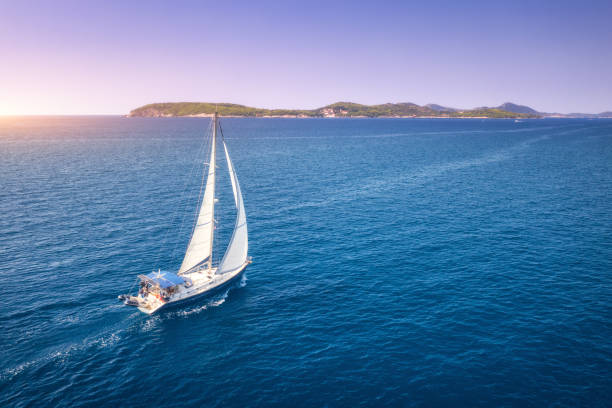 vue aérienne du beau voilier blanc dans la mer bleue à la soirée ensoleillée lumineuse d’été. mer adriatique en croatie. paysage avec le yacht, montagnes, eau bleue transparente, ciel au coucher du soleil. vue supérieure du bateau - morning croatia blue sea photos et images de collection