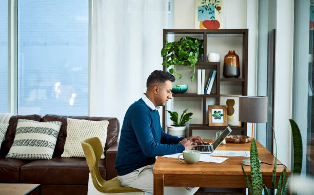 With the right setup you can make remote work, work Shot of a businessman using a laptop while working from home working from home stock pictures, royalty-free photos & images