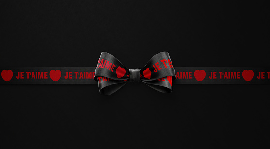 Love You ( Je T'aime in French ) written black ribbon over black background. Horizontal composition with copy space. Love, courtship, dating, engagement, relationships concept. Copy space available