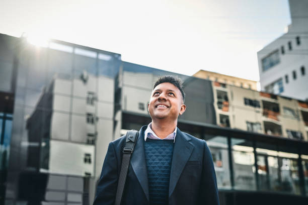 A new day opens a new door Shot of a businessman standing in the city and looking up hopefully town of hope stock pictures, royalty-free photos & images