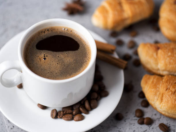istock white cup of espresso coffee, coffee beans, cinnamon, with small croissants. Coffee break 1294436610
