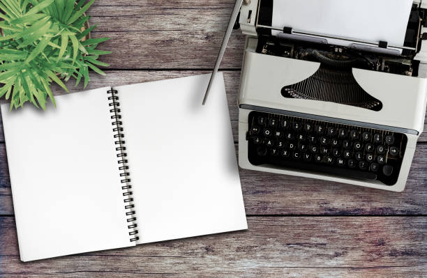 above view of old typewriter and spiral notepad on rustic wooden desk