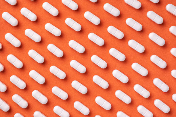 흰색 알약과 태블릿, 매크로오렌지와 빨간색 의학 배경. - orange pill close up large group of objects 뉴스 사진 이미지