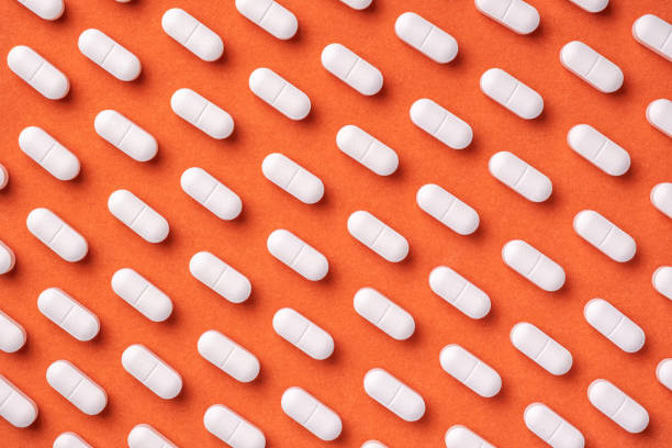 istock Orange and red medicine background with white pills and tablet, macro. 1294438543