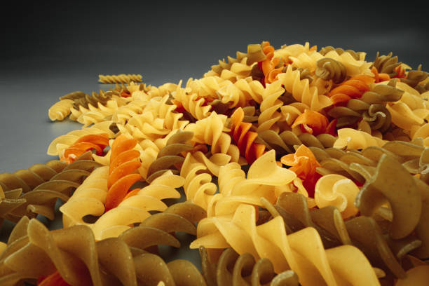 istock Uncooked pasta swirls on dark background macro 1294438667