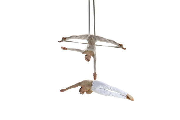istock Couple of young acrobats, circus athletes isolated on white studio background. Training perfect balanced in flight 1294441664