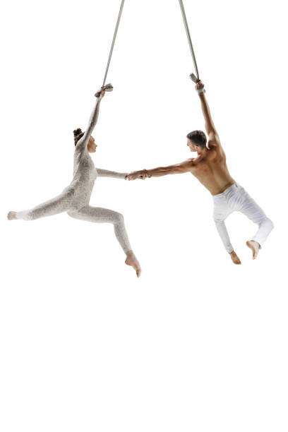 istock Couple of young acrobats, circus athletes isolated on white studio background. Training perfect balanced in flight 1294441701